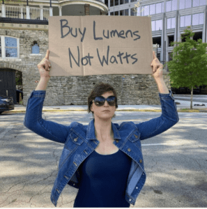 A women hold the board show "buy lumen not wattage"